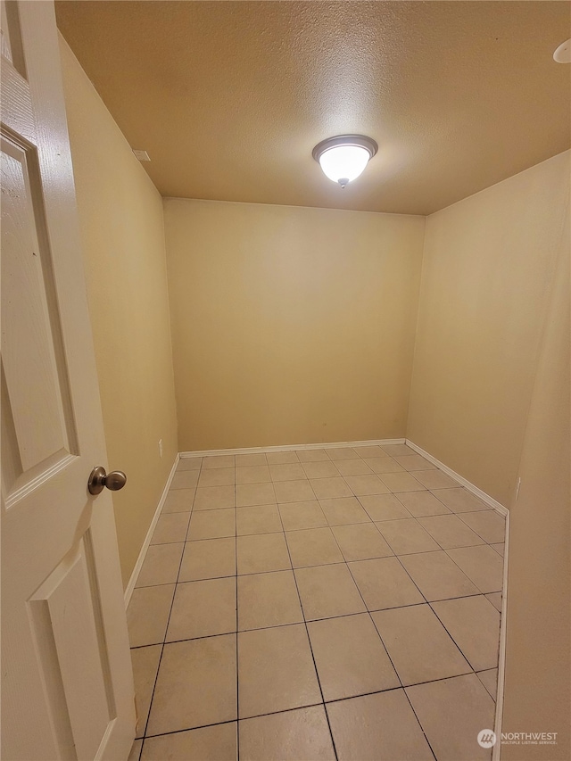 empty room with light tile patterned flooring and a textured ceiling