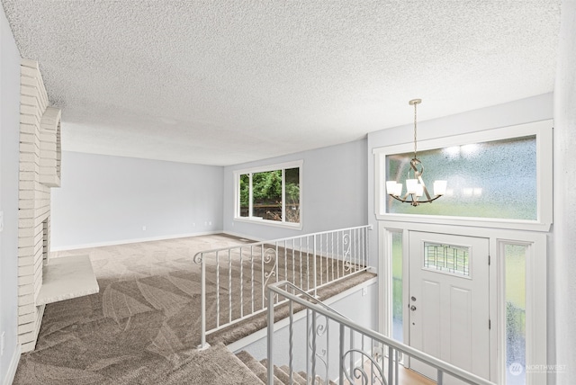 staircase with carpet flooring, a textured ceiling, and a notable chandelier