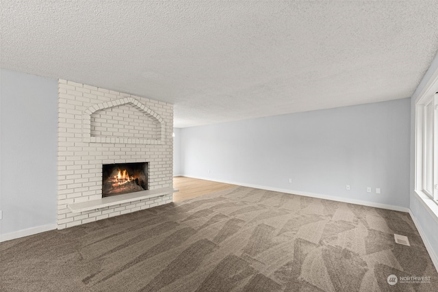 unfurnished living room with carpet flooring, a textured ceiling, and a fireplace