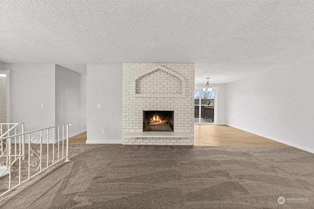 unfurnished living room featuring a fireplace, a textured ceiling, hardwood / wood-style flooring, and a notable chandelier