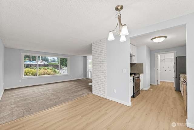 kitchen featuring gas range oven, pendant lighting, white cabinets, and light hardwood / wood-style flooring