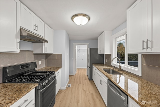 kitchen featuring dark stone countertops, white cabinetry, sink, and stainless steel appliances