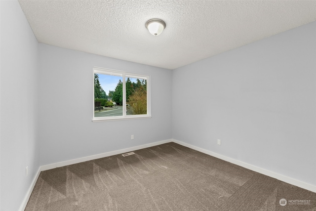 carpeted empty room with a textured ceiling