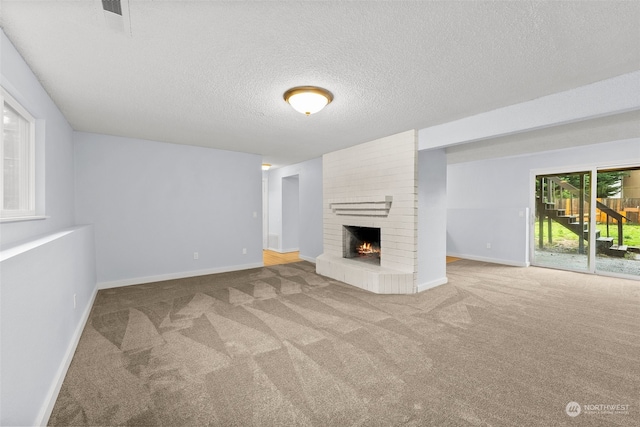 unfurnished living room with carpet flooring, a textured ceiling, and a brick fireplace