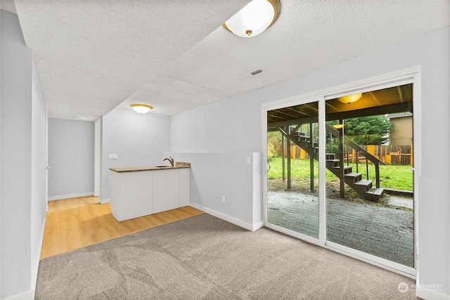 unfurnished living room with sink, wood-type flooring, and a textured ceiling