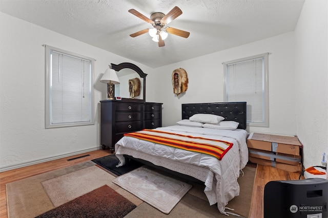 bedroom with ceiling fan, hardwood / wood-style floors, and a textured ceiling