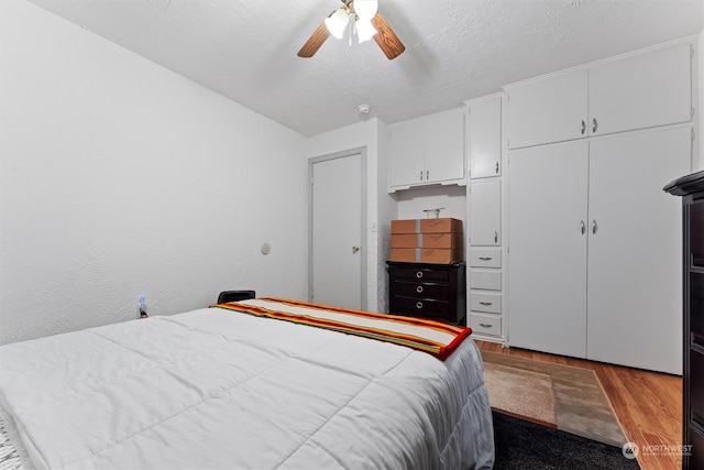 bedroom with ceiling fan, light wood-type flooring, a textured ceiling, and a closet