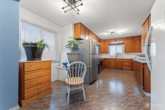 310 W 3rd Ave, Ritzville, WA 99169 - kitchen with stainless steel appliances, brown cabinets, a sink, light countertops, and a chandelier