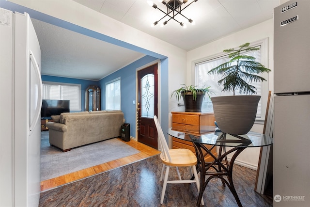 dining space with hardwood / wood-style floors, lofted ceiling, and an inviting chandelier