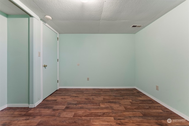 empty room with dark wood-type flooring and a textured ceiling