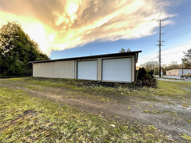 garage at dusk featuring a yard