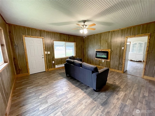 living room with a baseboard heating unit, a glass covered fireplace, ceiling fan, and wood finished floors