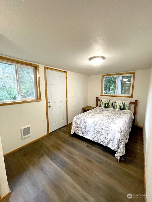 2820 State Route 105, Grayland, WA 98547 - bedroom with wood finished floors, multiple windows, baseboards, a wall mounted AC, and a textured ceiling
