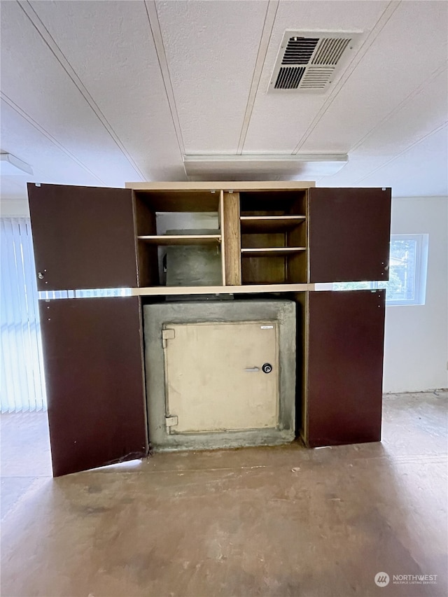 interior details with visible vents, a textured ceiling, and unfinished concrete floors