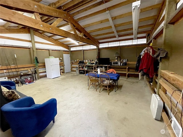 interior space featuring a garage, vaulted ceiling, and concrete flooring