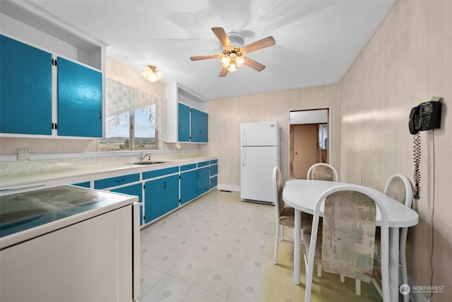 kitchen featuring blue cabinetry, ceiling fan, sink, white fridge, and range