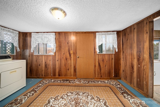 interior space with washer / dryer, a textured ceiling, and wood walls