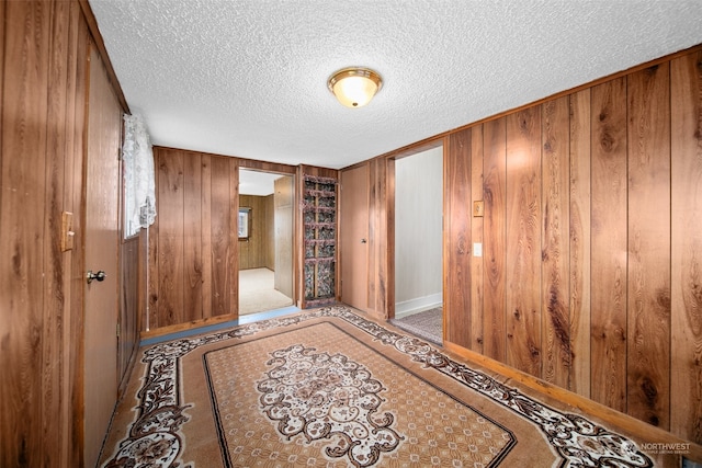 hallway featuring a textured ceiling and wood walls