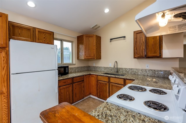 kitchen with sink, dark stone counters, lofted ceiling, white appliances, and light tile patterned flooring