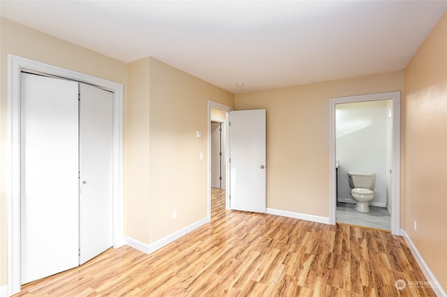 unfurnished bedroom featuring ensuite bath, a closet, and light hardwood / wood-style floors