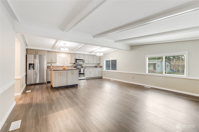 kitchen featuring appliances with stainless steel finishes, vaulted ceiling with beams, decorative light fixtures, a center island, and dark hardwood / wood-style floors