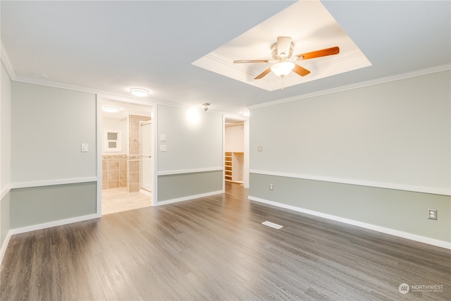 empty room with ceiling fan, wood-type flooring, crown molding, and a tray ceiling