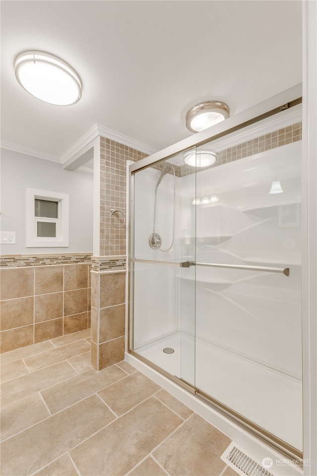 bathroom with crown molding, tile walls, and a shower with shower door