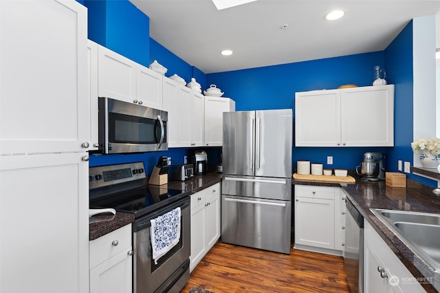 kitchen featuring sink, dark hardwood / wood-style flooring, white cabinets, and appliances with stainless steel finishes