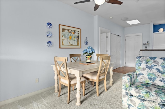 carpeted dining room featuring a skylight and ceiling fan