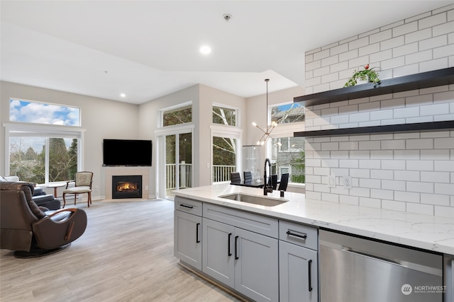 kitchen featuring dishwasher, light stone countertops, sink, and hanging light fixtures