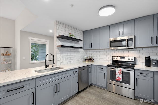 kitchen with gray cabinetry, light wood-type flooring, sink, and appliances with stainless steel finishes