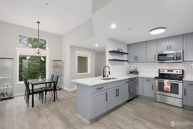 kitchen with gray cabinetry, sink, an inviting chandelier, light hardwood / wood-style flooring, and appliances with stainless steel finishes