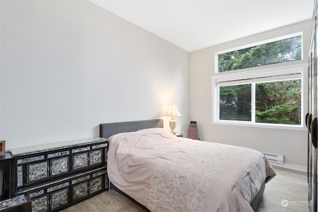 bedroom featuring lofted ceiling, light wood-type flooring, a baseboard radiator, and multiple windows