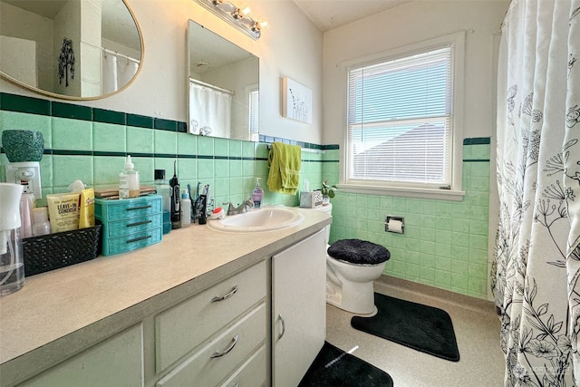 bathroom featuring vanity, tile walls, and toilet