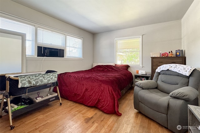 bedroom with multiple windows, hardwood / wood-style floors, and cooling unit