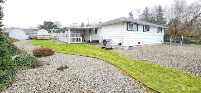 back of property featuring ac unit, a shed, and a yard