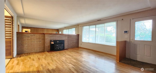 unfurnished living room featuring light wood-type flooring and a wood stove