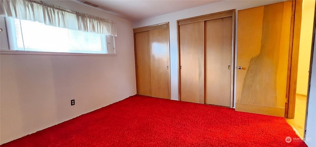 unfurnished bedroom with carpet floors and two closets