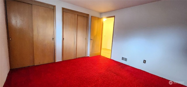 unfurnished bedroom featuring multiple closets and carpet floors