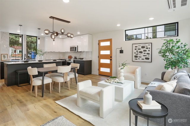 living room featuring light wood-type flooring, a notable chandelier, and sink