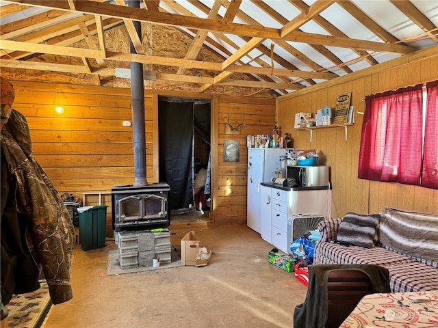 living room featuring a wood stove, wooden walls, and lofted ceiling