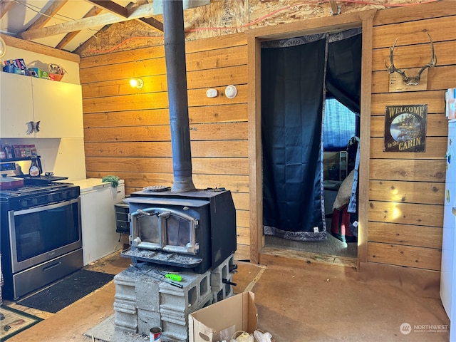 interior space featuring stainless steel range oven, a wood stove, and wooden walls