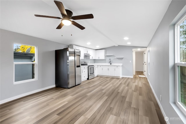 kitchen with appliances with stainless steel finishes, vaulted ceiling, light hardwood / wood-style floors, and white cabinetry