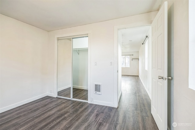 unfurnished bedroom featuring a barn door, dark hardwood / wood-style flooring, and a closet