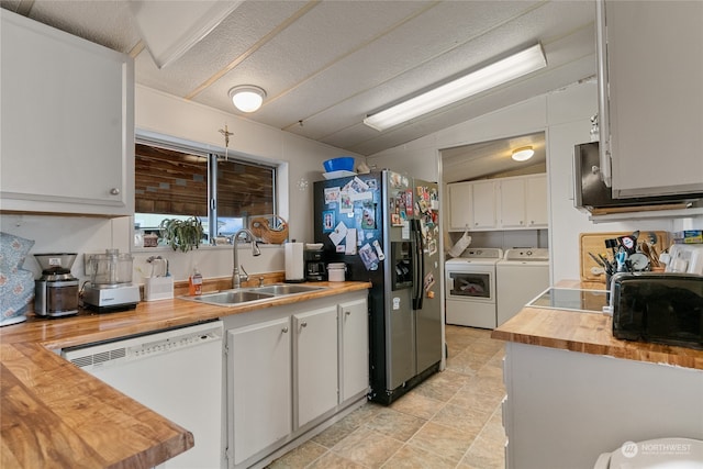 kitchen featuring washer and clothes dryer, lofted ceiling, white cabinets, white dishwasher, and sink