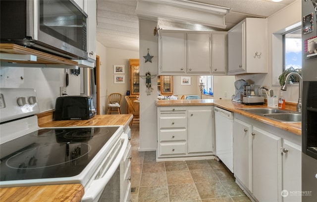 kitchen featuring white cabinets, kitchen peninsula, white appliances, and sink