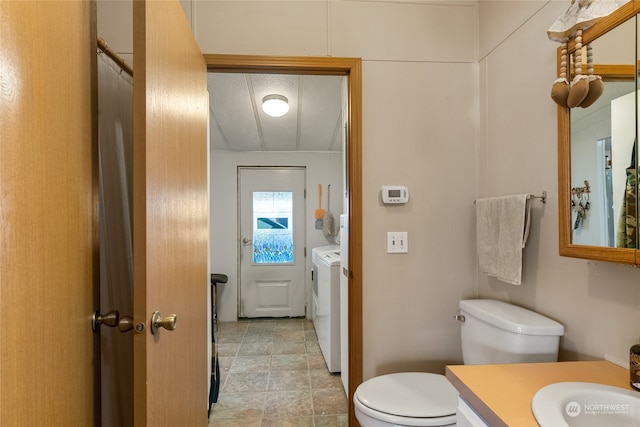 bathroom with independent washer and dryer, vanity, and toilet