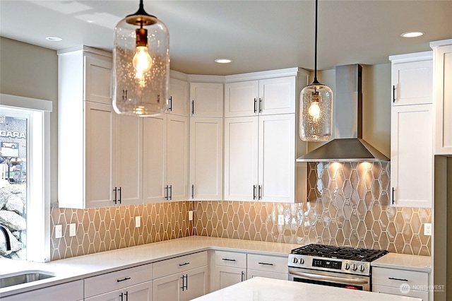 kitchen with white cabinetry, stainless steel gas stove, wall chimney exhaust hood, and hanging light fixtures