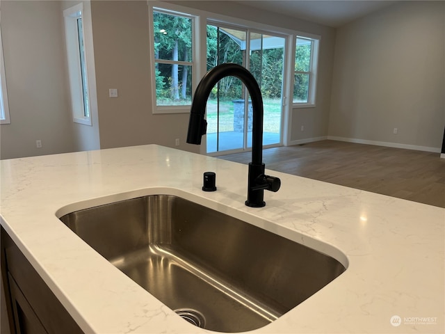 interior details with hardwood / wood-style floors, light stone counters, and sink