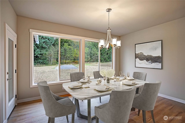 dining area with hardwood / wood-style floors and a notable chandelier